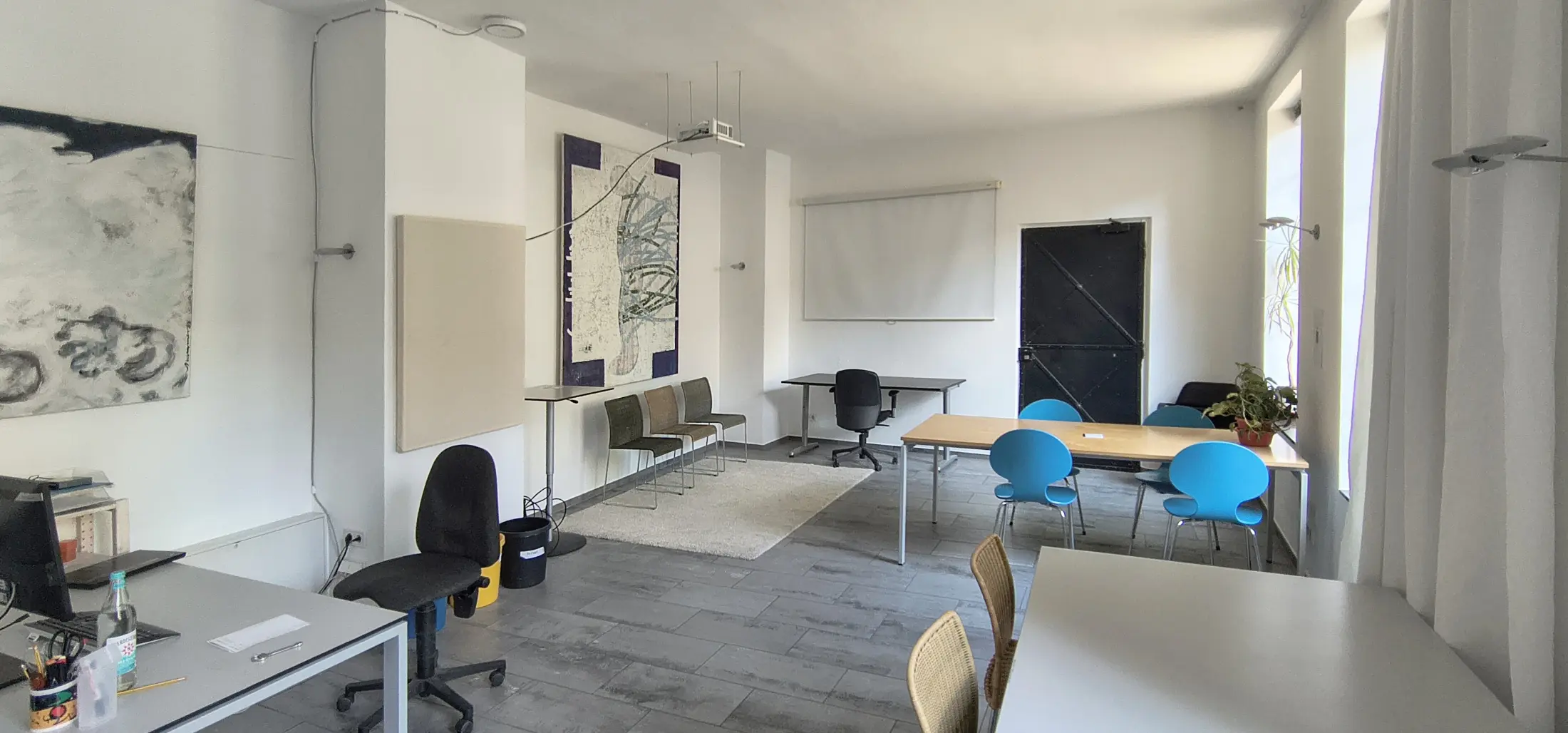 Arbeitsplätze mit Wandbild, Beamer und blauen Stühlen